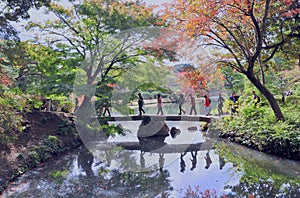 People walking on the bridge in traditional japanese public garden in Tokyo.