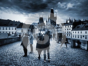 People are walking on the Charles Bridge, which is one of the landmarks of Prague