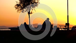 People walking, cycling and sitting on a chair on the recreation area during sunset, backlight