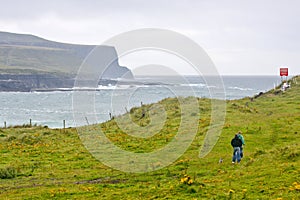 People walking a dog at Doolin Bay, Ireland