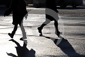 Black silhouettes and shadow of people walking down on a city street