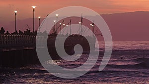 People walking and fishing on Forte dei Marmi`s pier at sunset