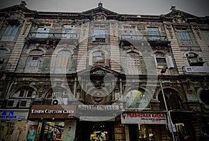 people walking in front of an old building with broken windows