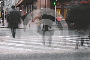 People walking on a large urban street, a pedestrian crossing. Blurred zebra movement
