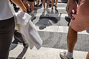 People walking over a cross walk on Fifth Avenue in New York City.