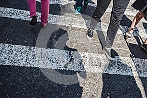 People walking over a cross walk on Fifth Avenue in New York City.