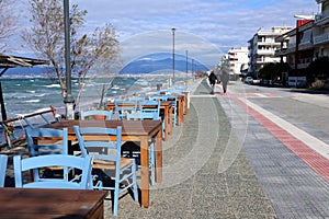 People walking on Peraia beach, Thessaloniki, Greece. View of colorful chairs and tables of a cafe.
