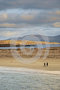 People walking on a sand. Dog bay beach county Galway, Ireland. Blue cloudy sky. Outdoor activity. Stunning Irish nature