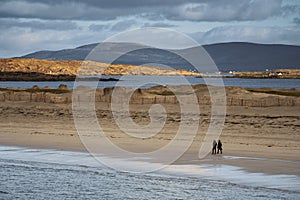 People walking on a sand. Dog bay beach county Galway, Ireland. Blue cloudy sky. Outdoor activity. Stunning Irish nature