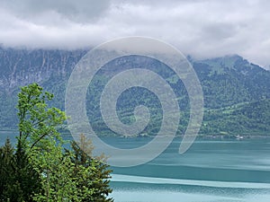 people walking with suitcases and water and mountains in the background