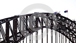 People walking on the Sydney Harbour Bridge with waving Australian flags