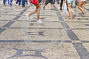 People walking in a typical Portuguese street paved in little stone