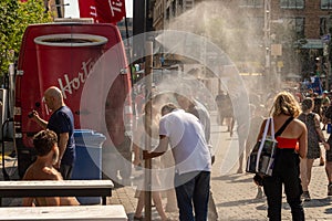 People walking under misting system to cool off during heatwave