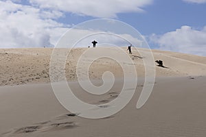 People walking up sand dunes on a bright sunny day in the desert