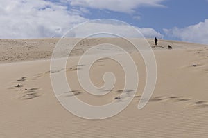 People walking up sand dunes on a bright sunny day in the desert