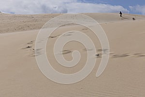 People walking up sand dunes on a bright sunny day in the desert