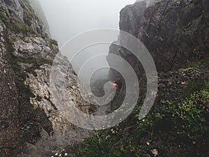 People walking up a steep mountain hiking path covered in fog and rain, swiss alps brienzer rothorn