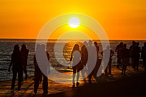 People walking on waterfront on sunset