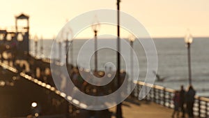 People walking, wooden pier in California USA. Oceanside waterfront vacations tourist resort.