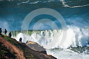 People watching big waves in Nazare, Portugal