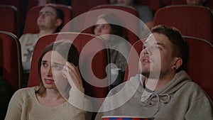 People watching scary film in movie theater. Young man sprinkling popcorn