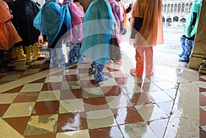 people with waterproof gaiters to protect their footwear during high tide on the island of Venice Italy