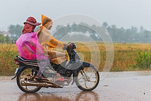 People wear packable raincoats while ride a scooter