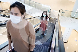 People,wearing protective face masks,using escalator by keep the distance at the white circles symbol on the escalator,safety,