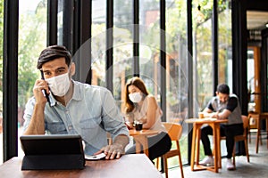 People wearing surgical masks are sitting in restaurants, coffee shops. social distancing concept Healthcare pandemic. Public