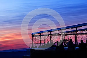 People in the well illuminated restaurant on the Uetliberg hill top enjoying evening sunset