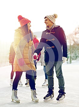 Happy friends ice skating on rink outdoors