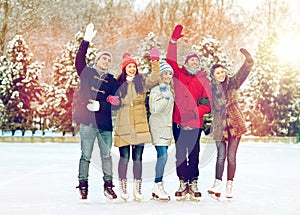 Happy friends ice skating on rink outdoors