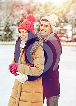 Happy couple ice skating on rink outdoors