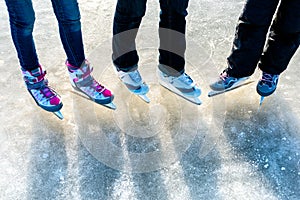 Winter sport and leisure concept - close up of legs of ice skaters on skating rink