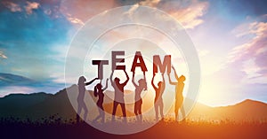 People, women and men holding TEAM word together at sunset, teamwork concept