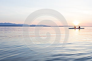 People women sea kayaking paddling boat in calm water together at sunset. Active outdoor adventure water sports. Journey,