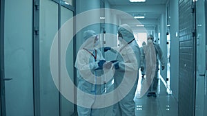 People work at clinic, wearing protective suits during pandemic.