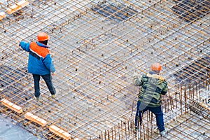 People work with reinforcement carcass made of fitness at construction site