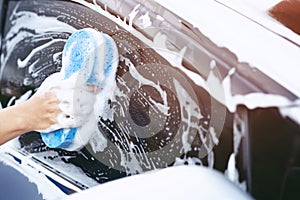 People worker man holding hand blue sponge and bubble foam cleanser window for washing car. Concept car wash clean.