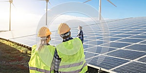 People working for alternative energy farm - Wind turbine power generators process and solar panels - Focus on helmets