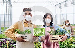 People working in greenhouse in garden center, store open after coronavirus lockdown.