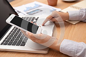 People working from home using smart phone and notebook laptop computer with blank black screen at workplace, anonymous face.