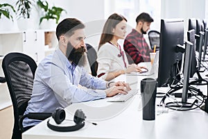 People working in modern IT office. Group of young and experienced programmers and software developers sitting at desks