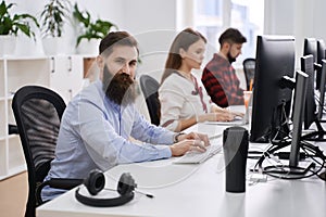 People working in modern IT office. Group of young and experienced programmers and software developers sitting at desks