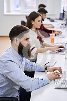 People working in modern IT office. Group of young and experienced programmers and software developers sitting at desks