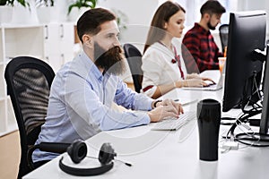 People working in modern IT office. Group of young and experienced programmers and software developers sitting at desks