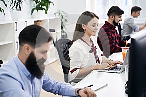 People working in modern IT office. Group of young and experienced programmers and software developers sitting at desks