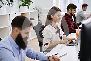 People working in modern IT office. Group of young and experienced programmers and software developers sitting at desks