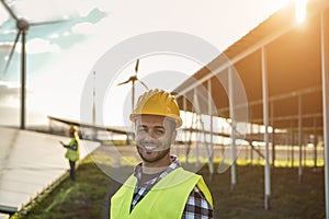 People working for solar panels and wind turbines - Renewable energy concept - Focus on man face