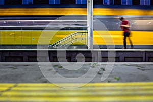 Pepople in a trainstation with motion blurred trains moving fast